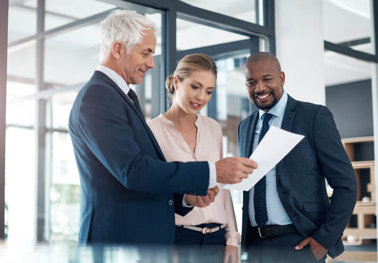 Des gens d’affaires discutant paperasse dans un bureau d’allure moderne.