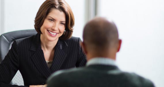 Une femme assise à son bureau en discussion avec son collègue.