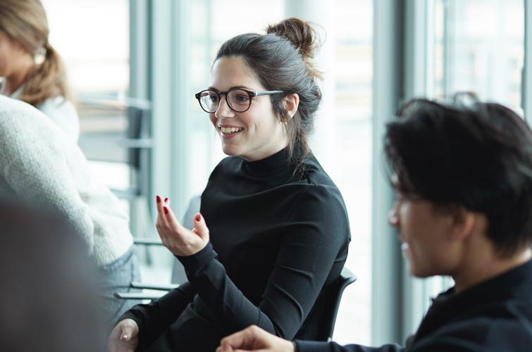 Une femme assise à une table de conférence est en pleine discussion.