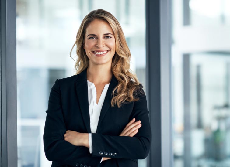 Une femme d’affaires souriante, les bras croisés.