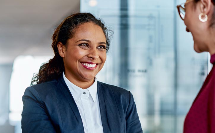Two professional women meeting in a lobby.