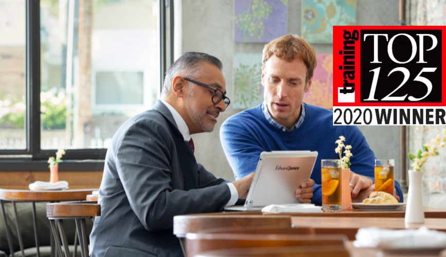 Two men looking at an ipad while eating.