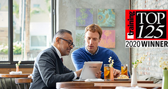 Two men looking at an ipad while eating.