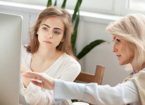 Two women looking at a computer monitor.