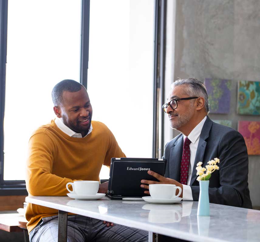 resourcesfocus856x796 Two professional men having a discussion in an office using an Edward Jones's tablet.
