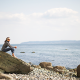 Woman relaxing on a rocky beach.