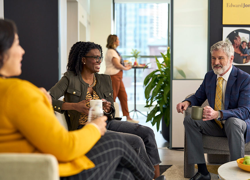 Two women and a man sitting discussing in an Edward Jones office.