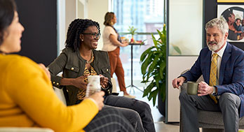 Two women and a man sitting discussing in an Edward Jones office.