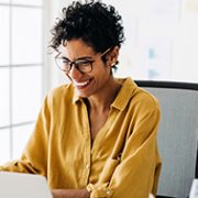 A women in looking at her laptop smiling.