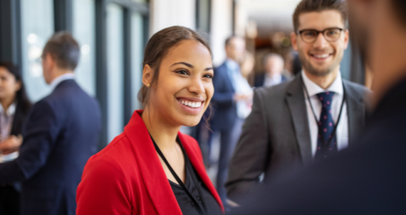 Female and male listening to a speaker in a casual, lobby setting.