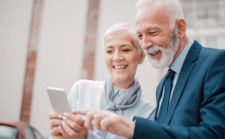 An elderly couple look at a mobile phone