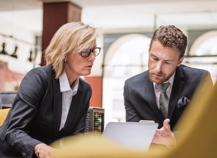 A man and woman looking down at a mobile phone.