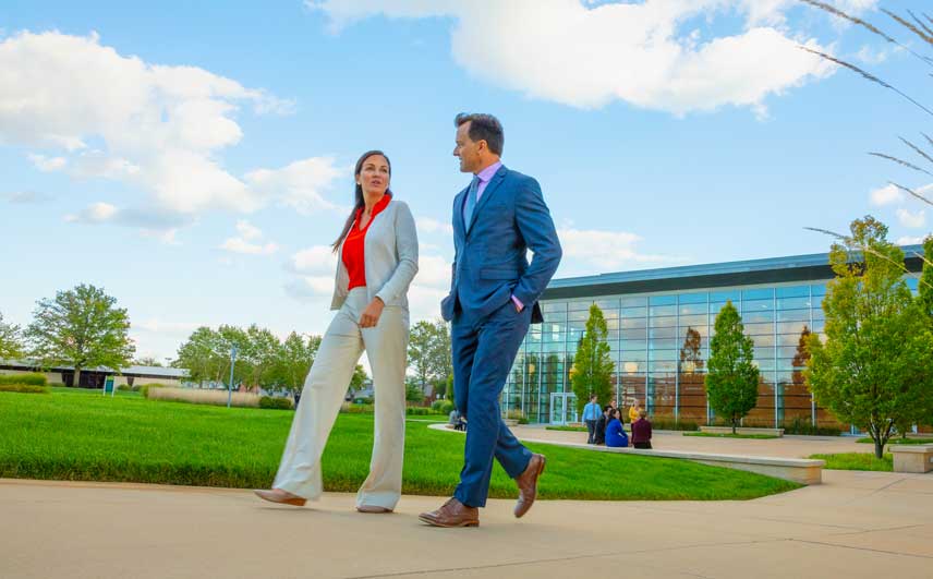 Professional man and woman having a discussion while on a walk outside.