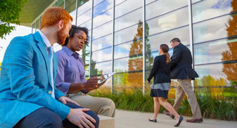 Coworkers sitting outside in a conversation.