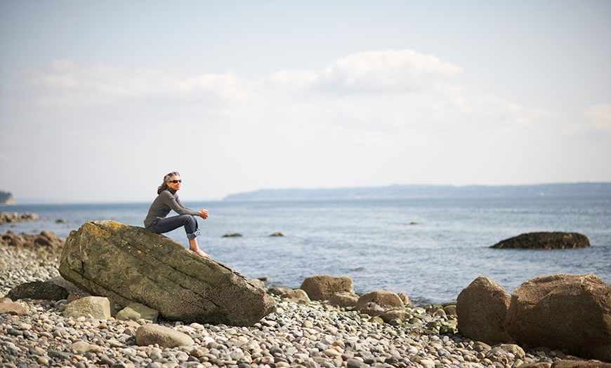 Woman relaxing on a rocky beach .
