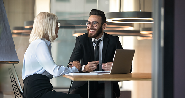 Man talking to a woman in an office in front of a laptop.