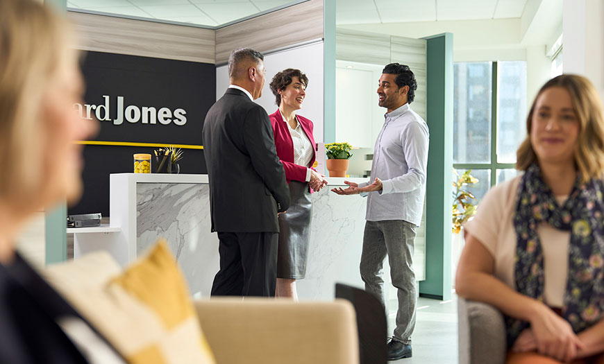 Women sitting and have discussion with a small group standing in the background talking in an Edward Jones office.