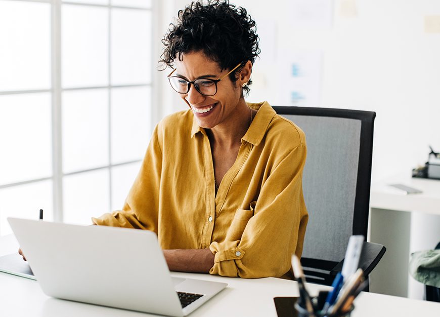 A women in looking at her laptop smiling.