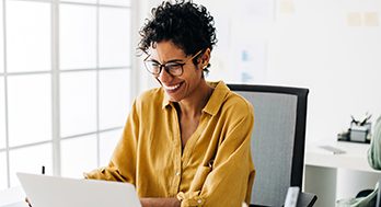 A women in looking at her laptop smiling.