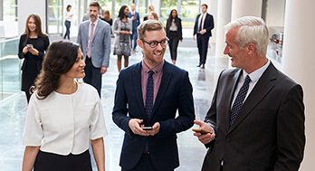 Two men and a woman walking and talking.