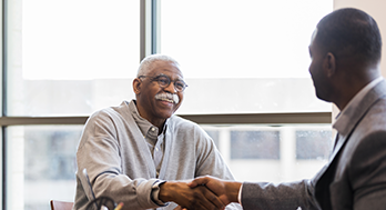 Two men shaking hands in office.