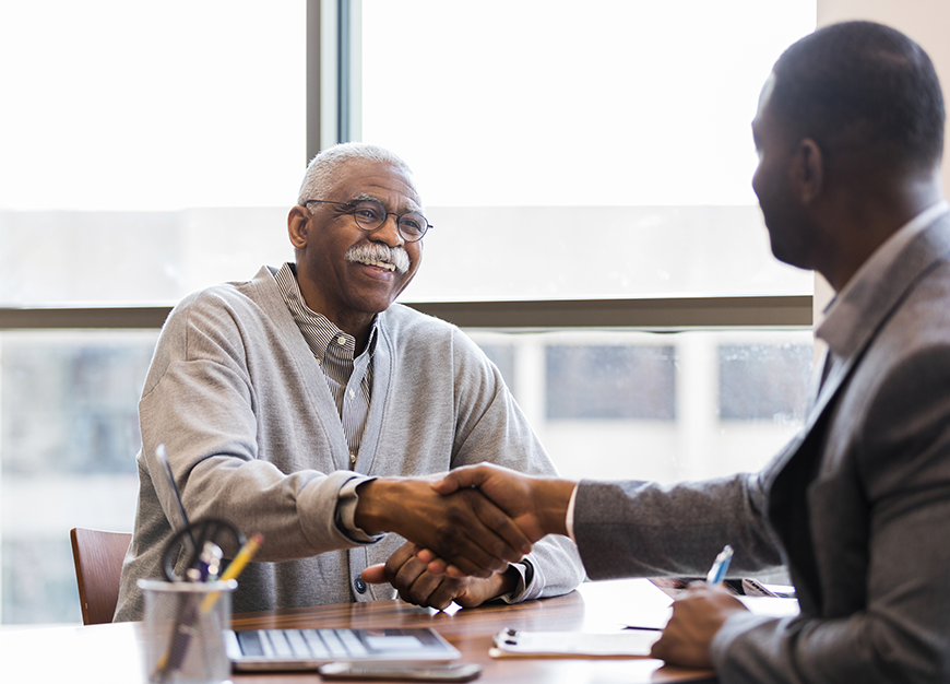 Two men shaking hands in office.