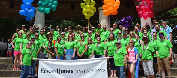 Un grand nombre d’associés en t-shirts verts, debout derrière une bannière sur les placements Edward Jones.